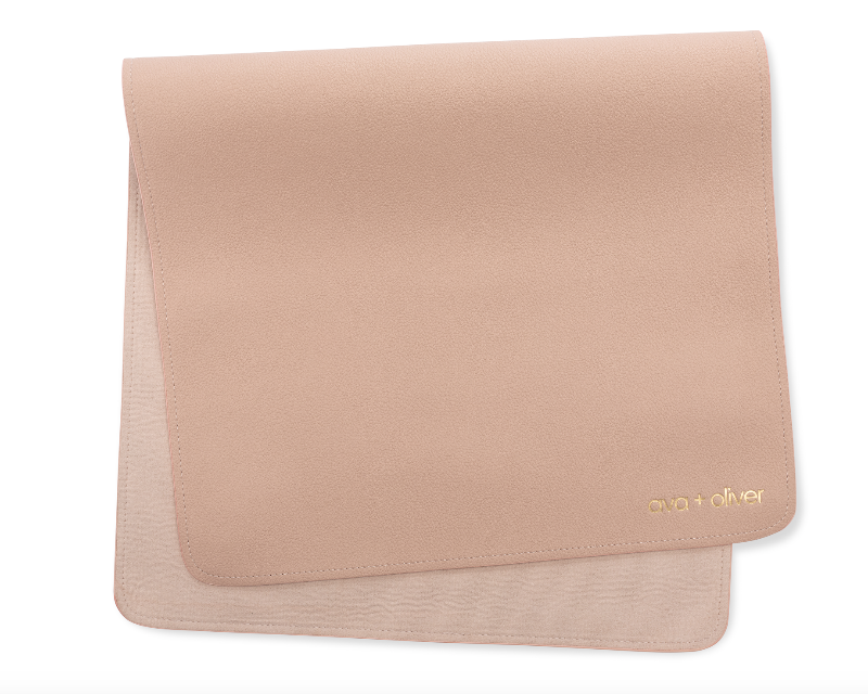 A folded vegan leather changing mat in pink sand color, with the brand name 'ava + oliver' visible on the bottom corner.